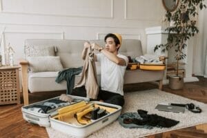 image of person packing a suitcase in a living room | boulder summer travel tips pack layers colorado music festivals